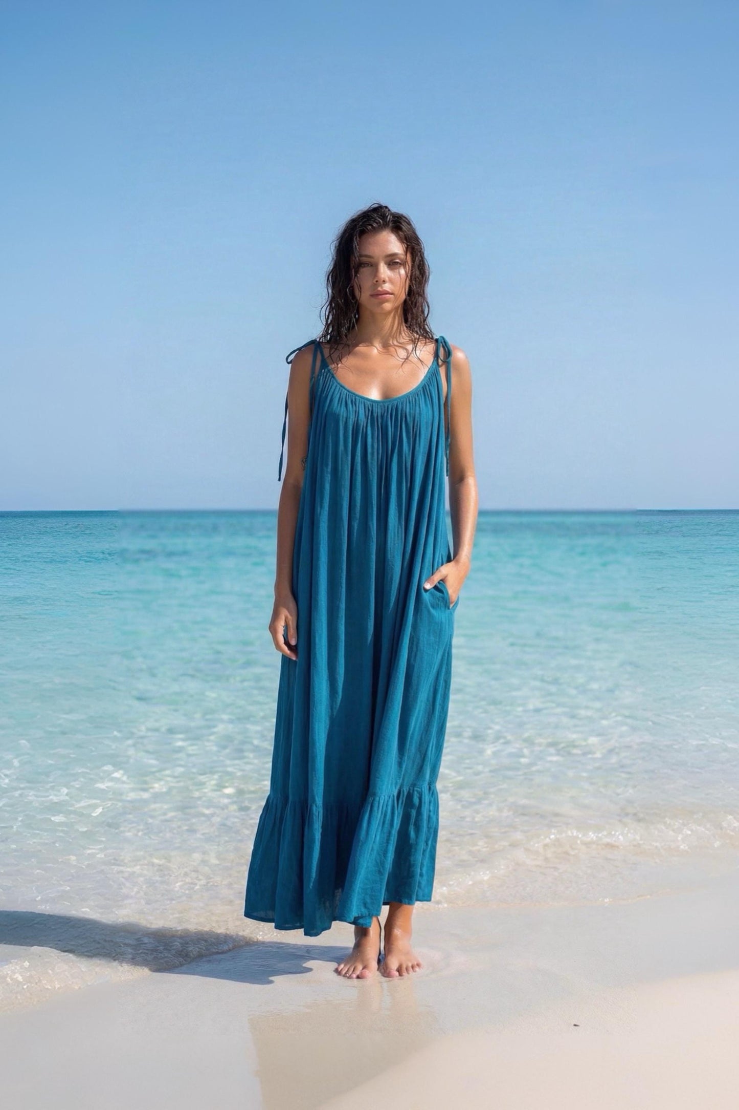 Blue turquoise open back maxi dress with tie shoulders and a flowy oversized fit on the beach.