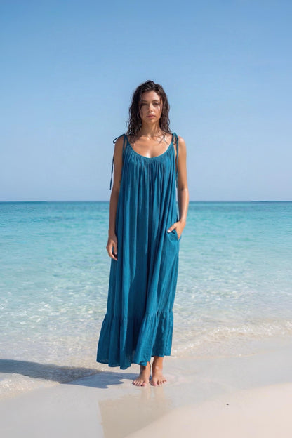 Blue turquoise open back maxi dress with tie shoulders and a flowy oversized fit on the beach.