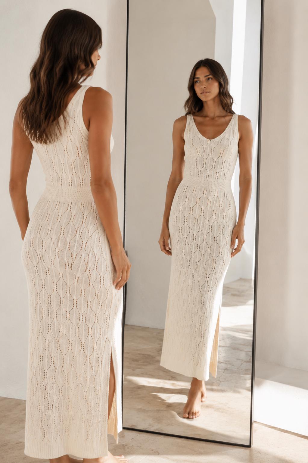 May include: A sleeveless cream-colored midi dress featuring a textured knit pattern with vertical leaf-like motifs, a V-neckline, a fitted waist section, and a side slit along the lower hem, shown from both a back and front perspective in a mirror.