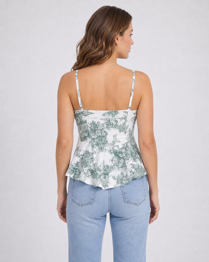 May include: A sleeveless peplum top featuring a white base with a detailed green toile de jouy pattern, thin adjustable spaghetti straps, and a square neckline, paired with light blue denim jeans that have a classic five-pocket design.
